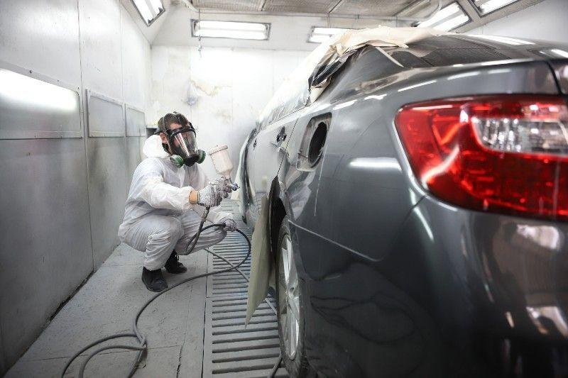 Technician refinishing a car in a paint booth